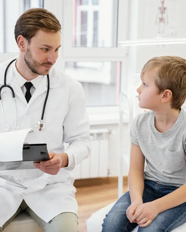 Médico conversando com menino no consultório